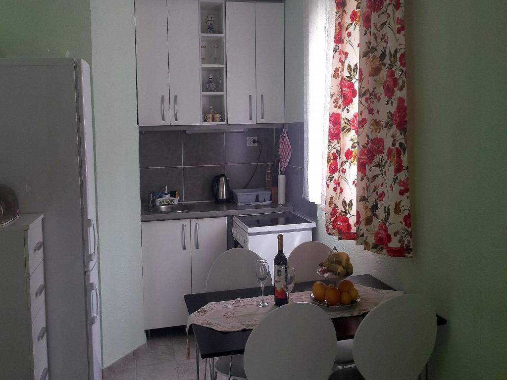 een keuken met een tafel en stoelen en een fles wijn bij Holiday Home Aksentijevic in Sutomore