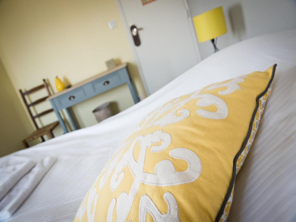 a yellow and white pillow sitting on a bed at Logis Hotel Restaurant Le Relais Fleuri in Vervins