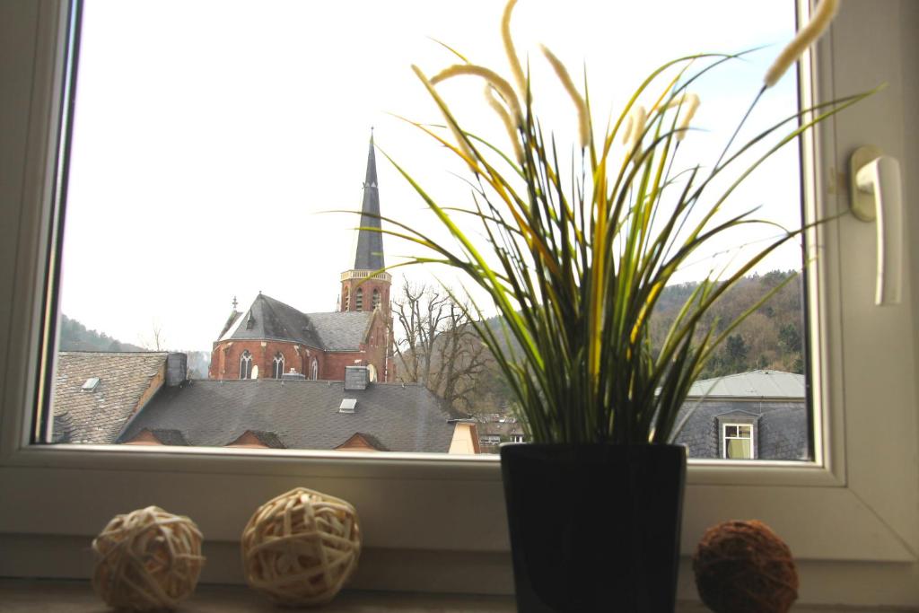 ein Fenster mit einer Topfpflanze und einer Kirche in der Unterkunft Ferienwohnung Kirchturmblick Euren in Trier