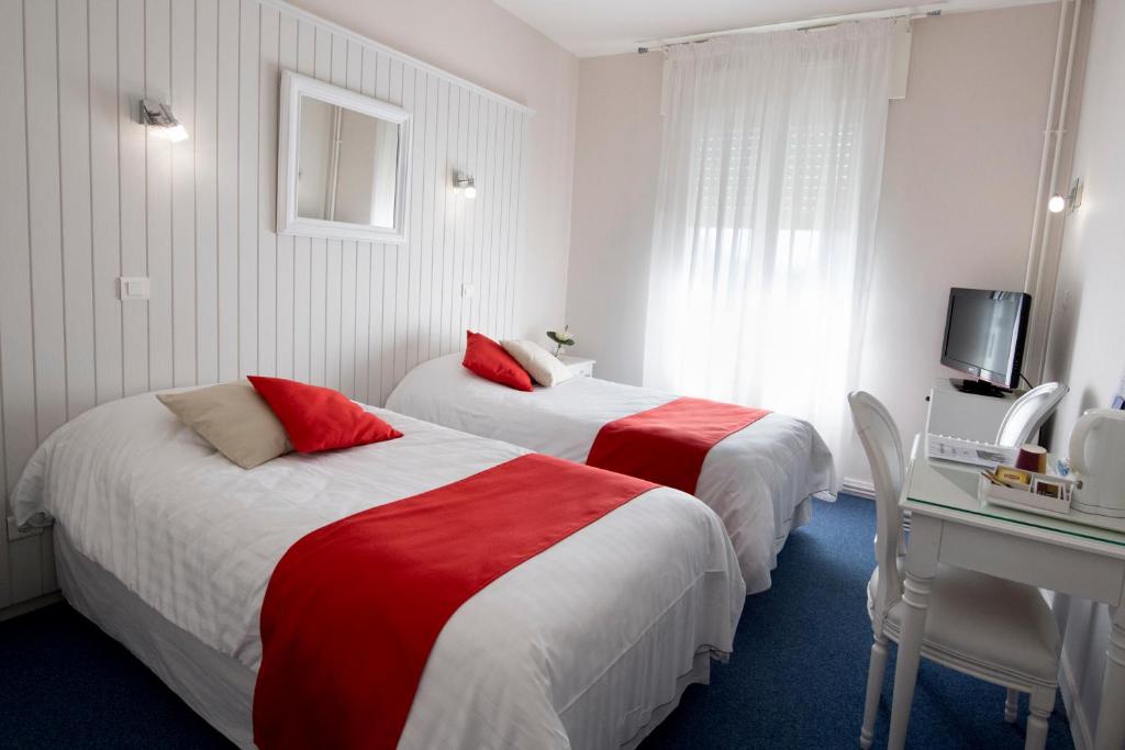 a hotel room with two beds and a desk at Hotel Biney in Rodez