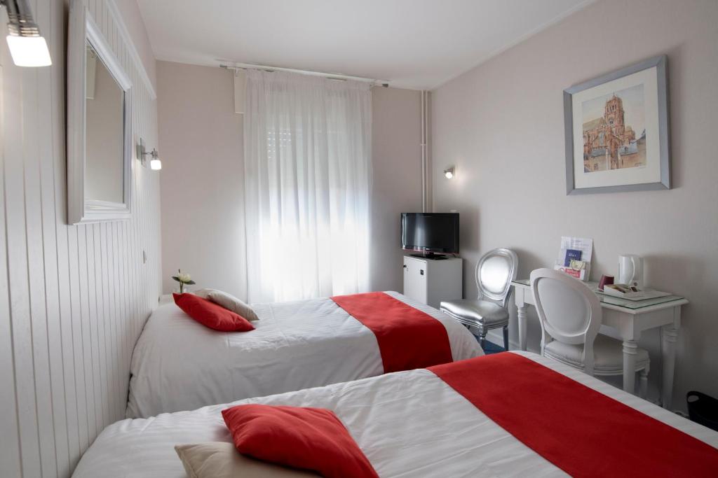 a hotel room with two beds and a desk at Hotel Biney in Rodez