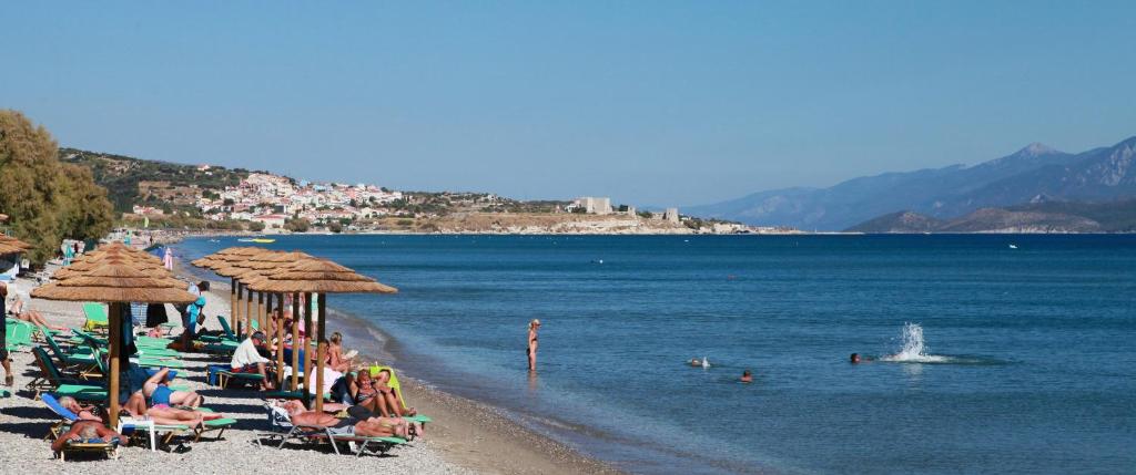 a group of people sitting on a beach with umbrellas at Hydrele Beach Hotel & Village in Potokáki