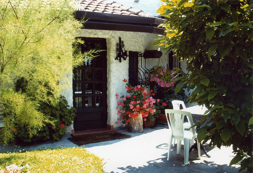 een witte stoel voor een huis met bloemen bij Case Vacanza la Ventura in Massarosa