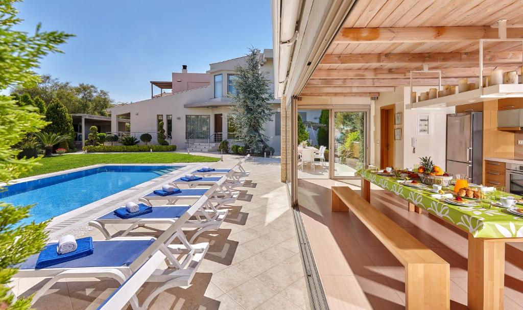 un patio al aire libre con mesas y sillas junto a una piscina en Villa EverGreen en Foinikiá