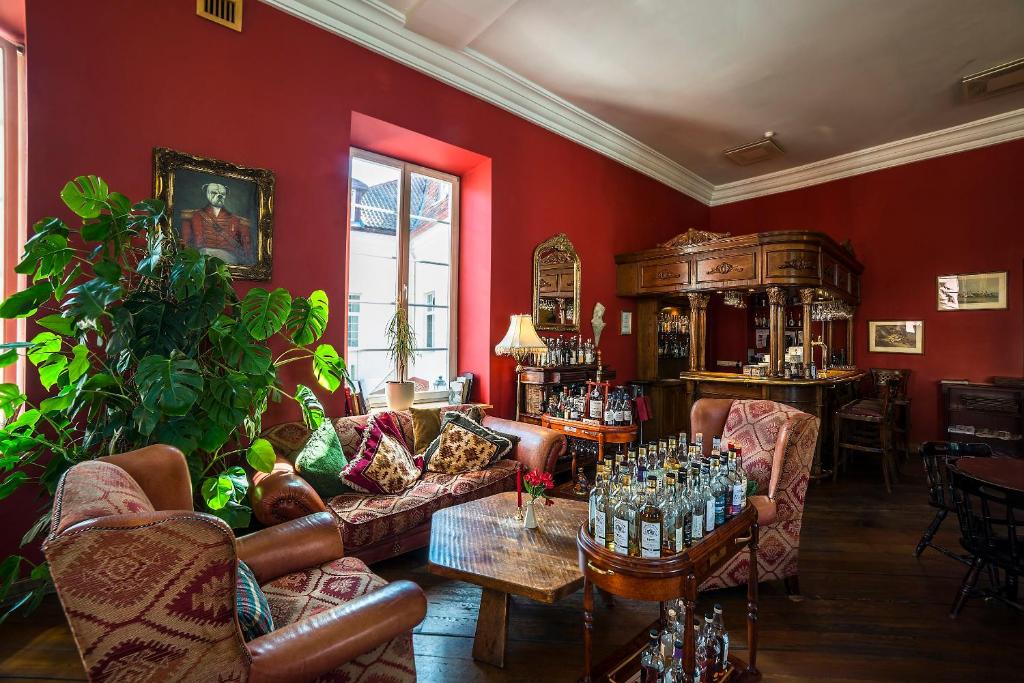 Shakespeare Boutique Hotel — Lounge with leather armchairs, patterned cushions, tropical plant, ornate bar cabinet and bottled spirits on a wooden cart
