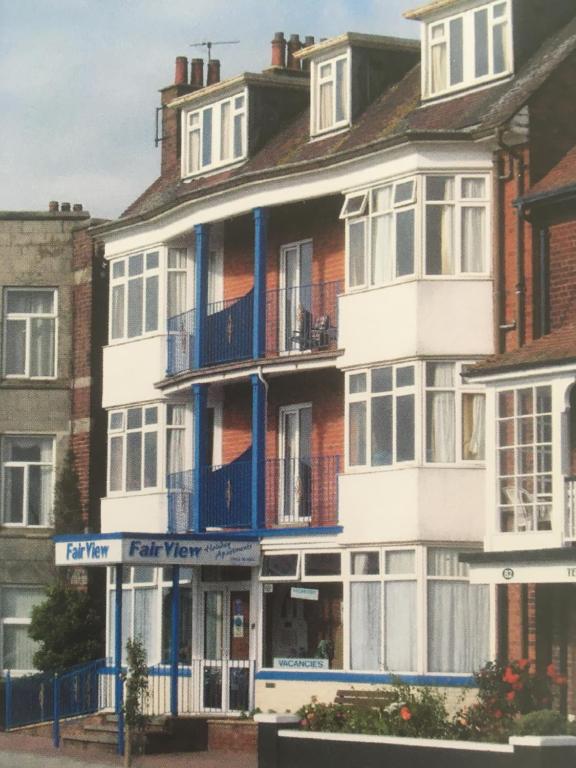 um grande edifício branco com varandas azuis numa rua em Fairview holiday flats em Skegness