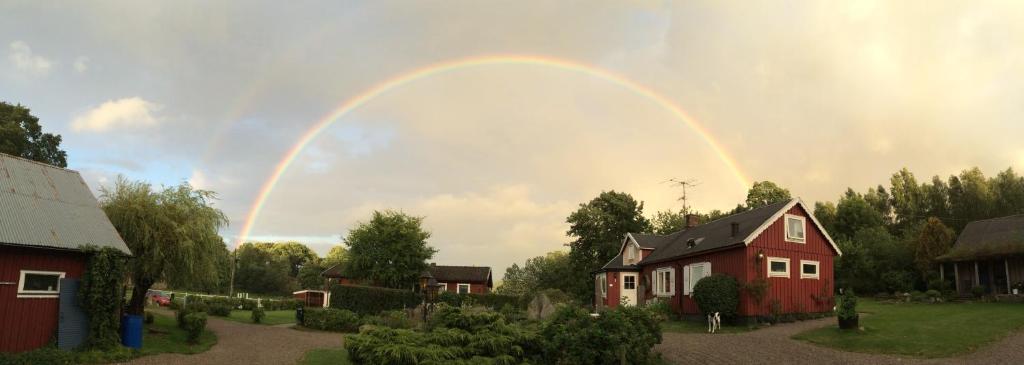 a rainbow in the sky over a red house at Tuvagård B&B Vindhästar in Långås