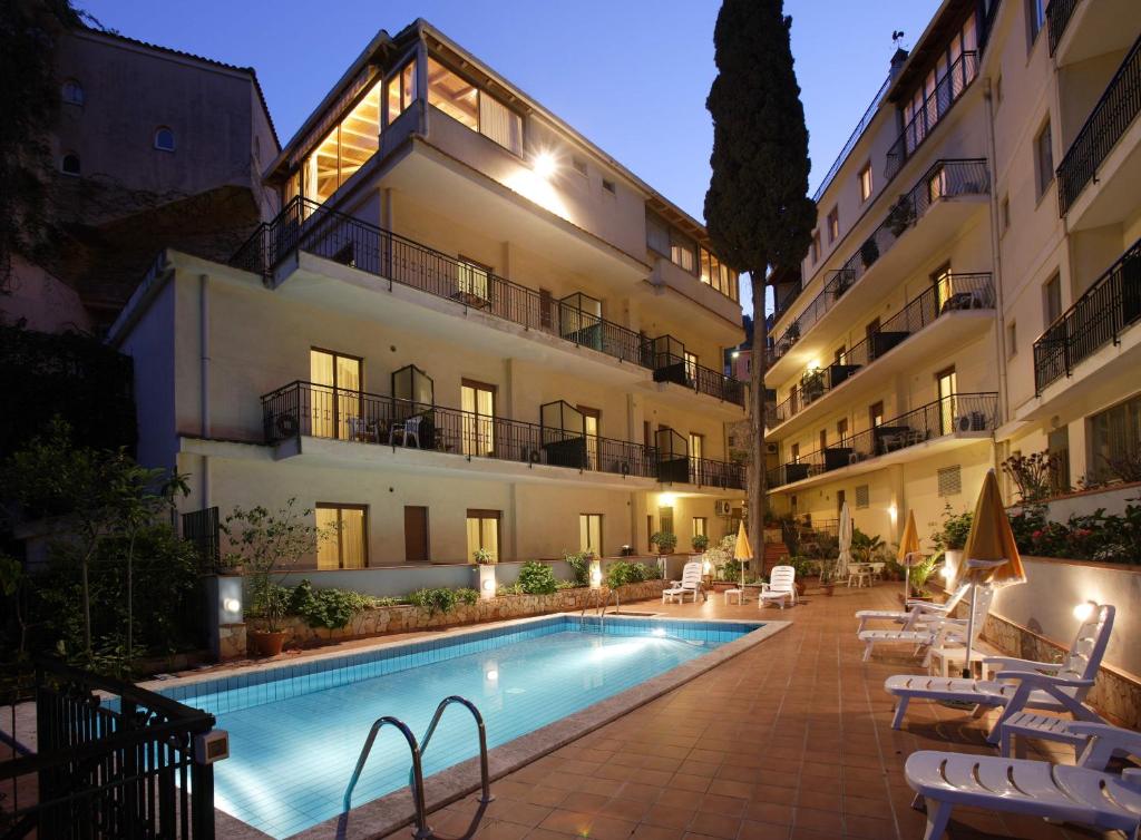 un hotel con piscina frente a un edificio en Hotel Soleado, en Taormina