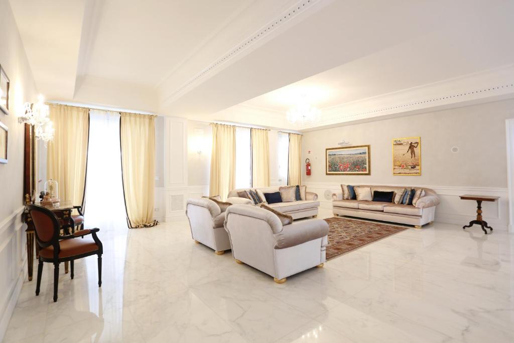 una gran sala de estar con muebles y ventanas blancos. en Tesoretto Hotel, en Poggiardo