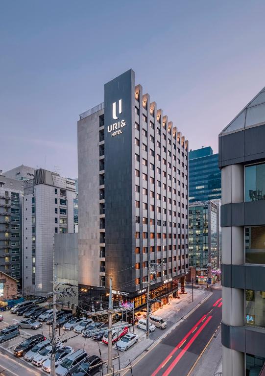 a large building with a sign on it in a parking lot at Hotel Uri& in Seoul