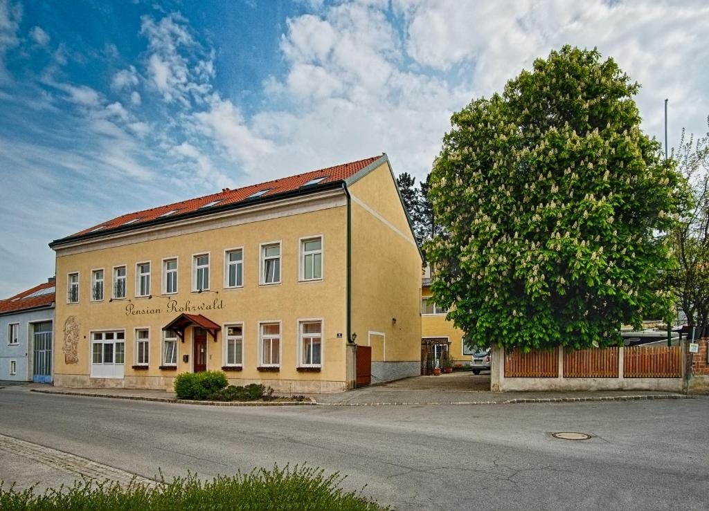 a building on the side of a street next to a tree at Pension Rohrwald in Oberrohrbach