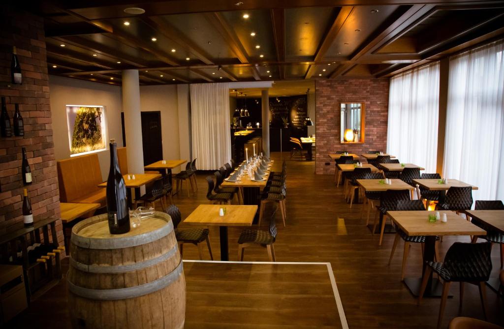 Rheinhessen Inn GmbH في Wörrstadt: مطعم بطاولات وكراسي وبرميل للنبيذ