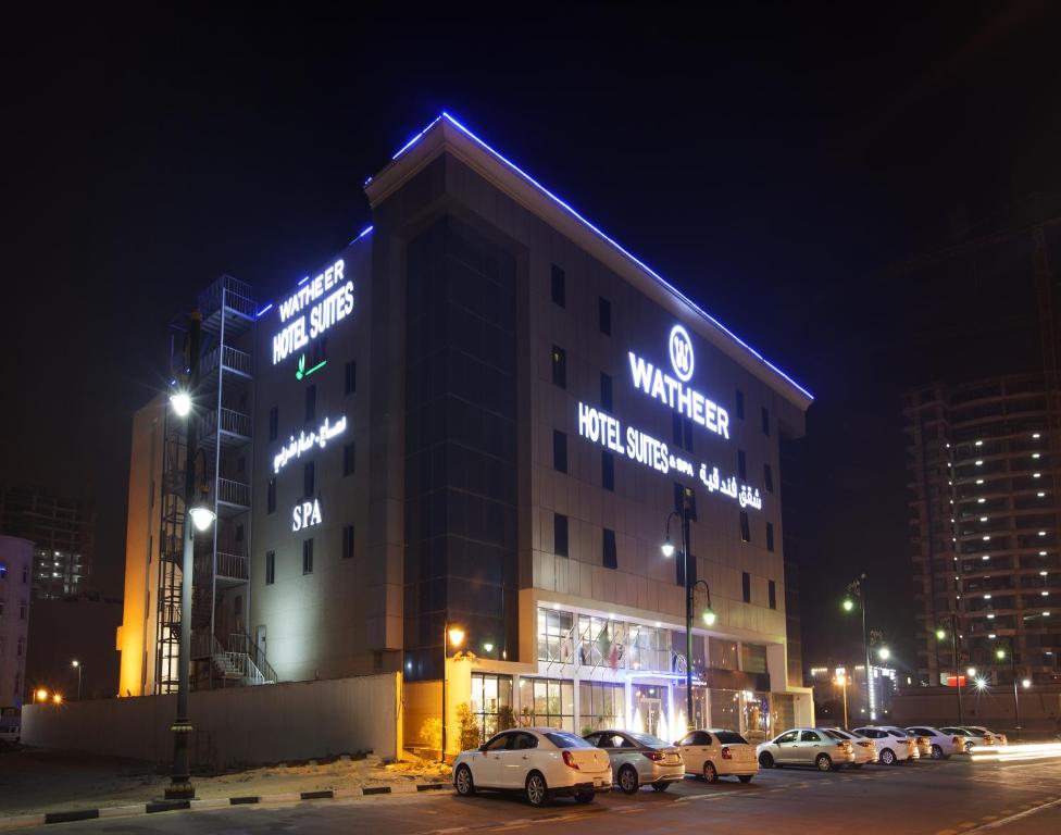 a building with cars parked in a parking lot at night at Watheer Hotel Suite in Dammam