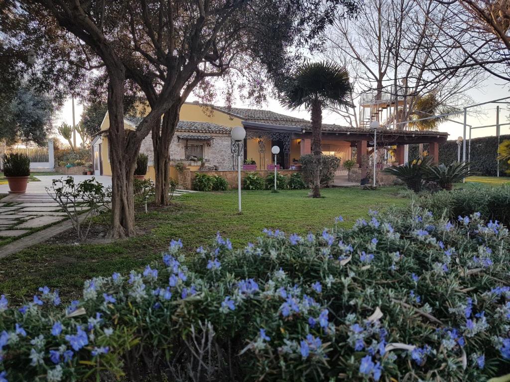 un giardino con fiori blu di fronte a un edificio di Villa Marinella ad Augusta
