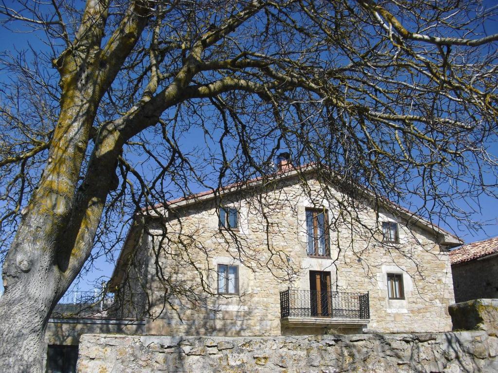 una vieja casa de piedra con un árbol delante en La Nogala, en Dobro