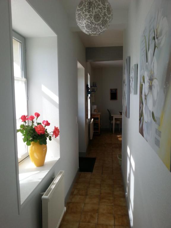 a hallway with a vase with red flowers on a window at Gîte A l'ombre de l'Abbaye in Faverolles-sur-Cher