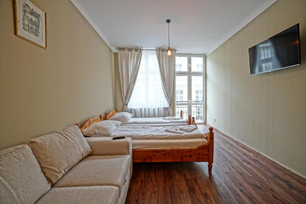 a bedroom with a bed and a couch and a window at Apartamenty Grodzka 8 in Krakow