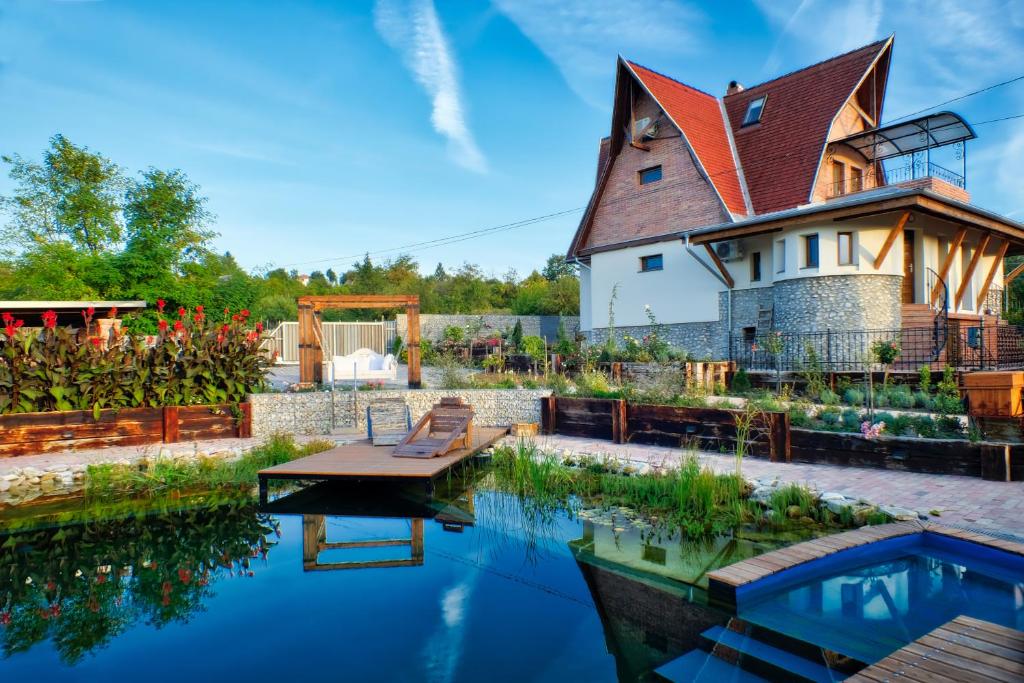 a house with a pond in front of it at Vintage Home Vendégház in Miskolctapolca