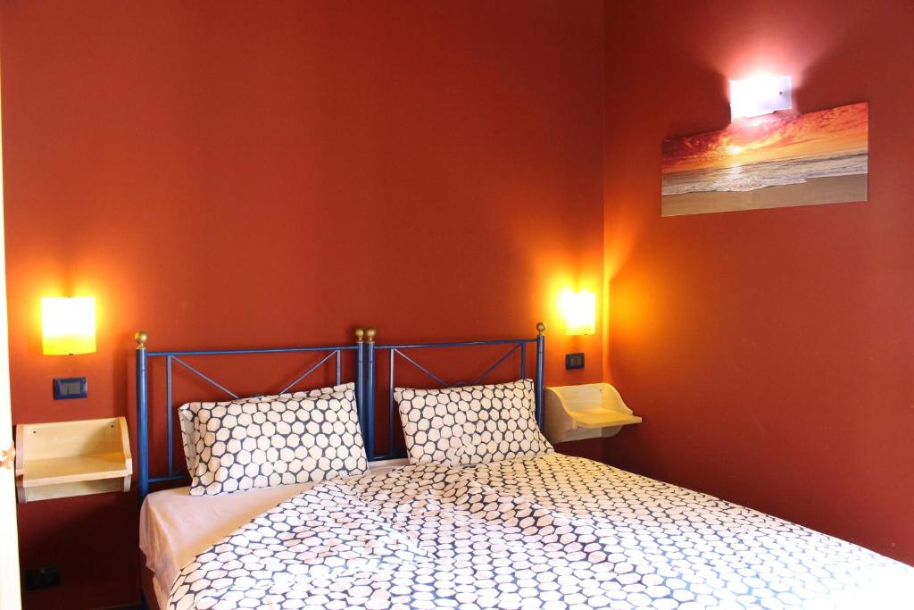 a bedroom with a bed with orange walls and two lights at CasaTua Punta Secca in Punta Secca