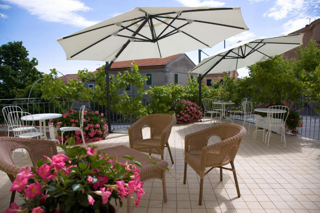 un patio con mesas, sillas y una sombrilla en Daniela Camere, en Sirolo