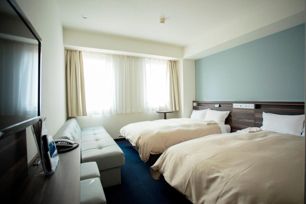 a hotel room with two beds and a couch at Hiroshima Pacific Hotel in Hiroshima