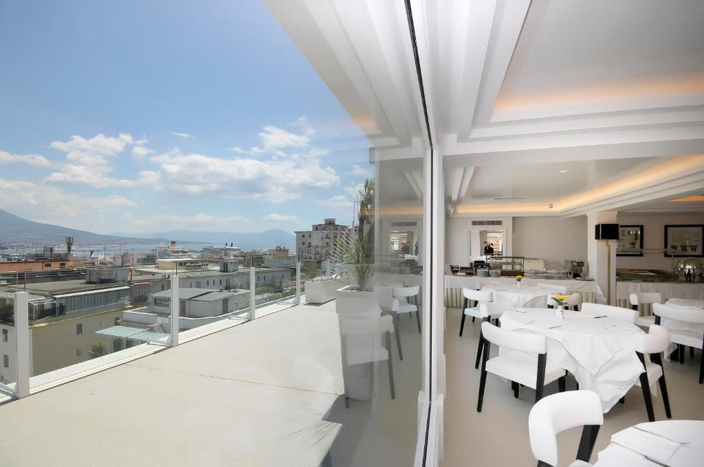un restaurante con mesas blancas y sillas en un balcón en Grand Hotel Oriente, en Nápoles