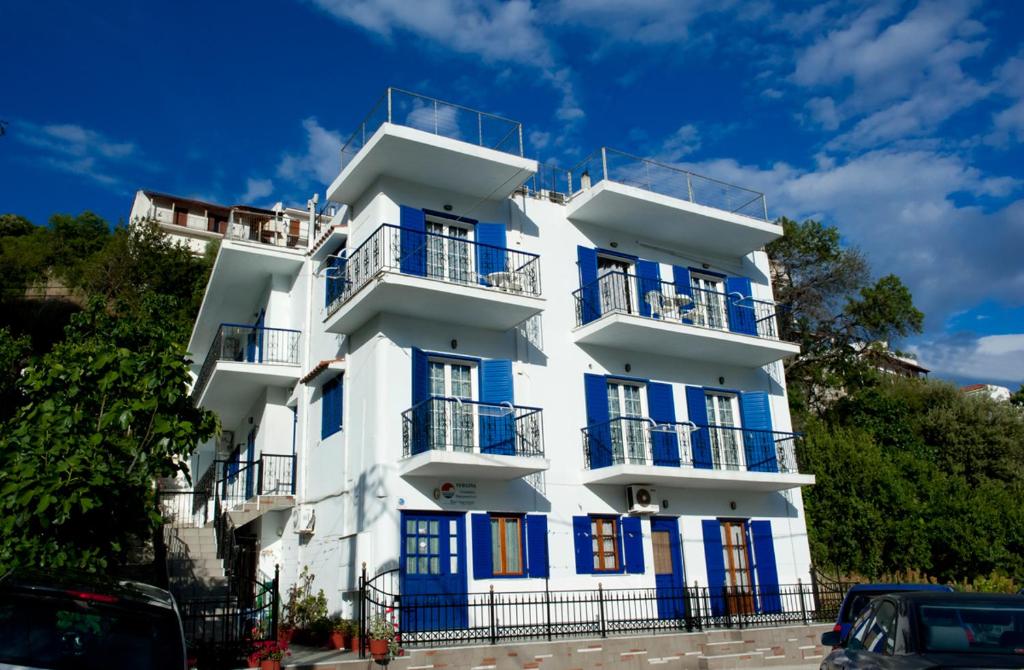 a white building with blue windows and balconies at Syraina Apartments in Skiathos Town