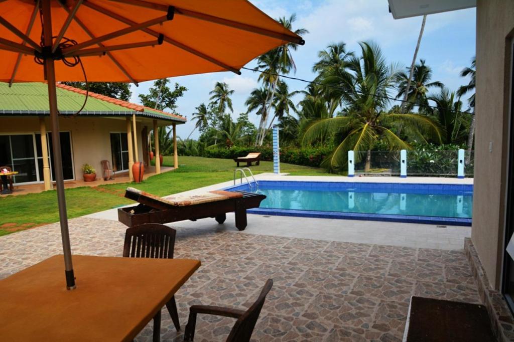 a table with an umbrella next to a swimming pool at The Hilltop Boosa in Galle