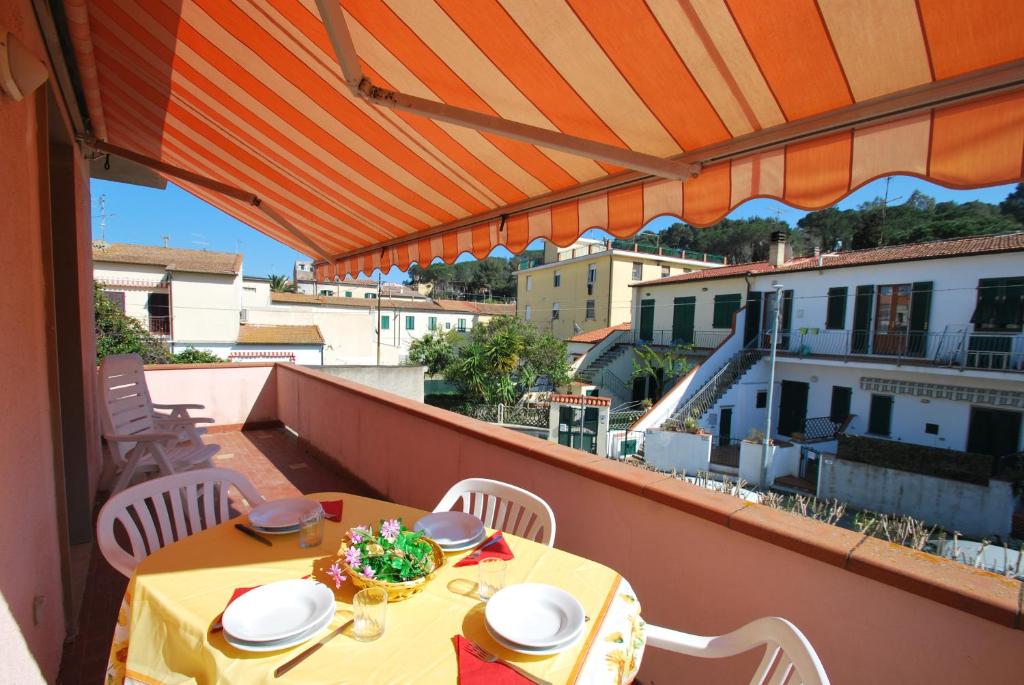 d'une table et de chaises sur un balcon avec un parasol dans l'établissement Appartamenti Camelia e Gabry - Zona mare con posti auto e terrazze, à Marina di Campo