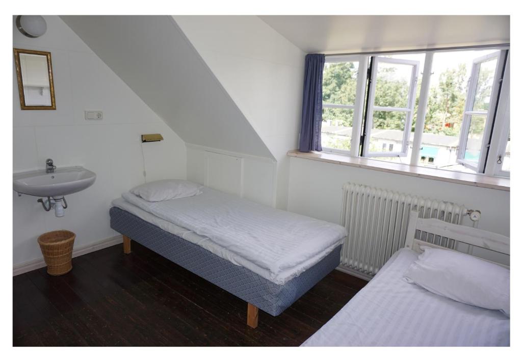 a bedroom with two beds and a sink and a window at STF Vandrarhem Backåkra in Löderup