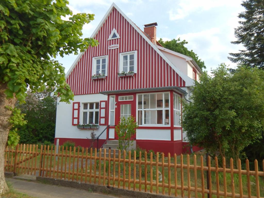 uma casa vermelha e branca com uma cerca em Ferienwohnungen Obstwiese & Sonnenschein em Himmelpfort