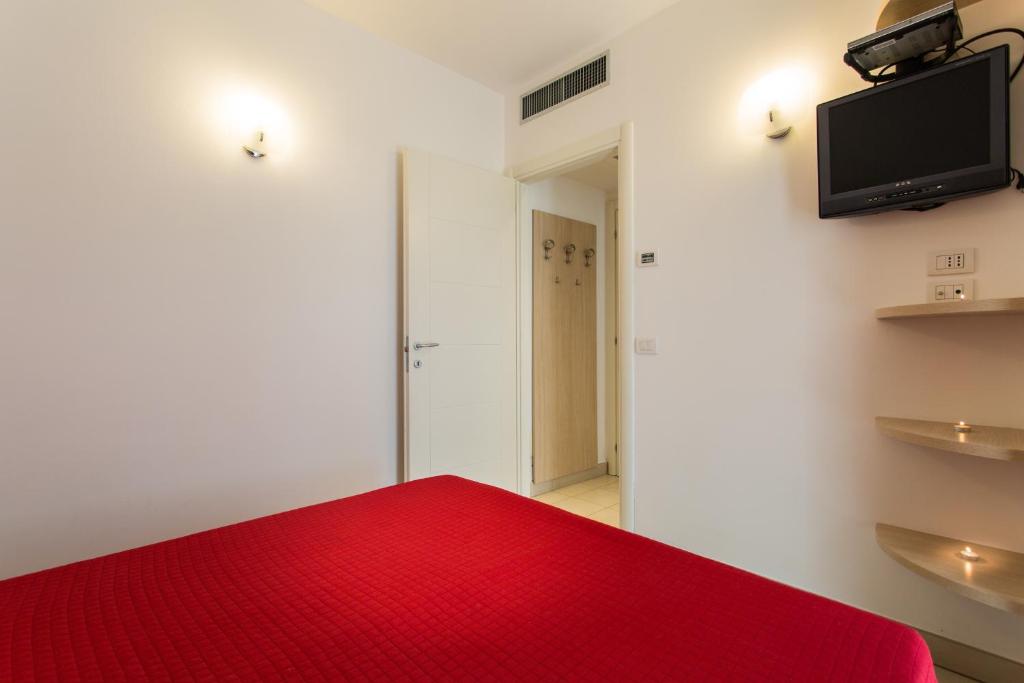 a room with a red bed and a flat screen tv at Wally Residence in Rimini