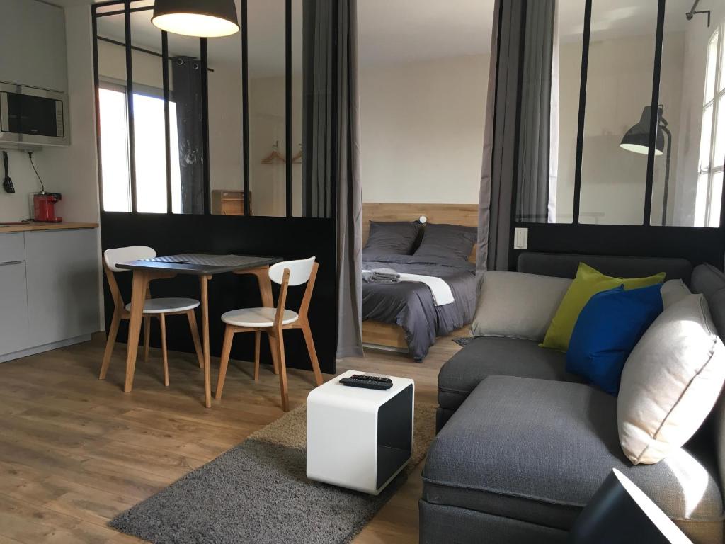 ein Wohnzimmer mit einer Couch, einem Tisch und einem Bett in der Unterkunft Appartements Les Rochelais in La Rochelle