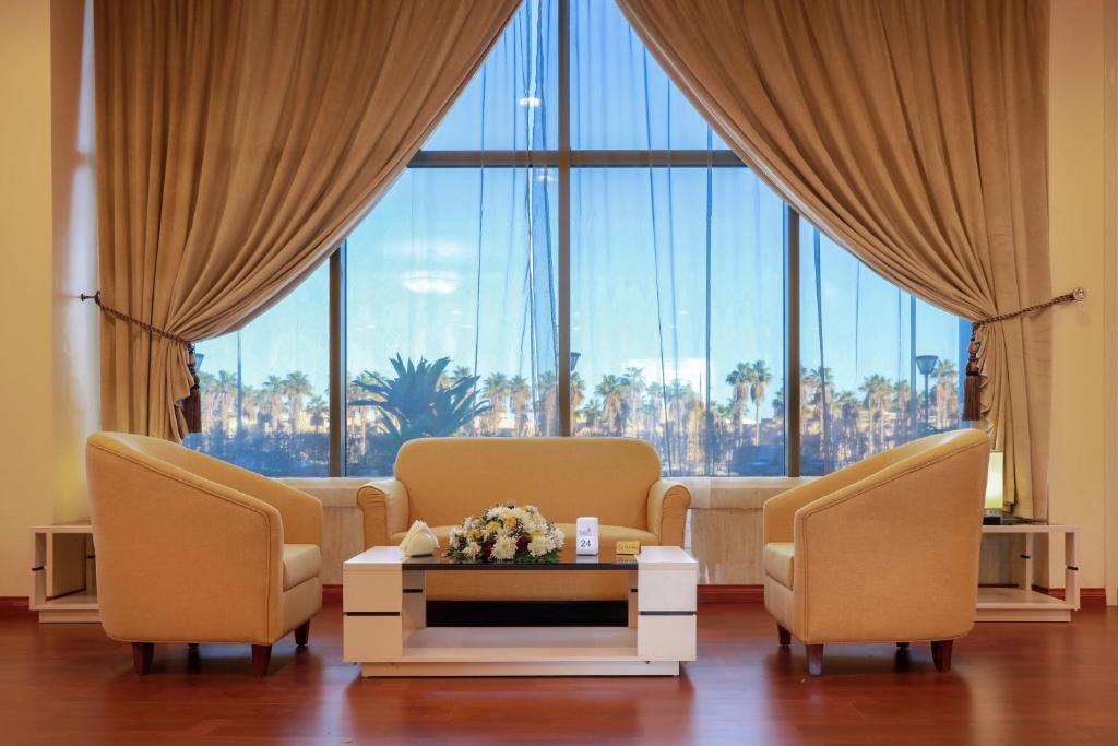a living room with two chairs and a table and a large window at Hala Inn Arar Hotel in Arar