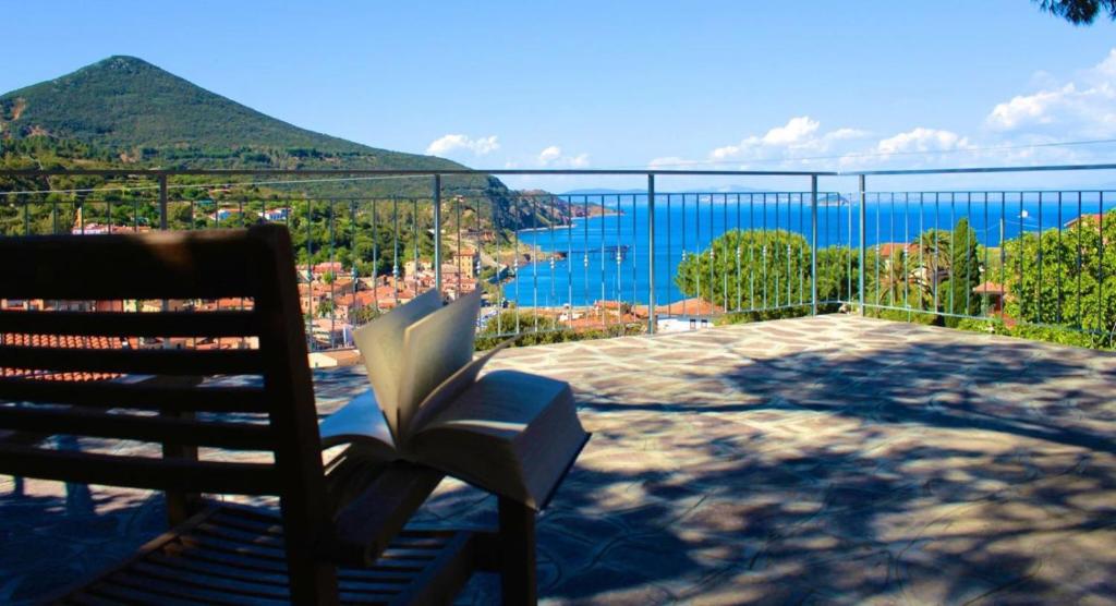 a book sitting on a bench with a view of the ocean at Appartamenti Estivi Anna e Pino in Rio Marina