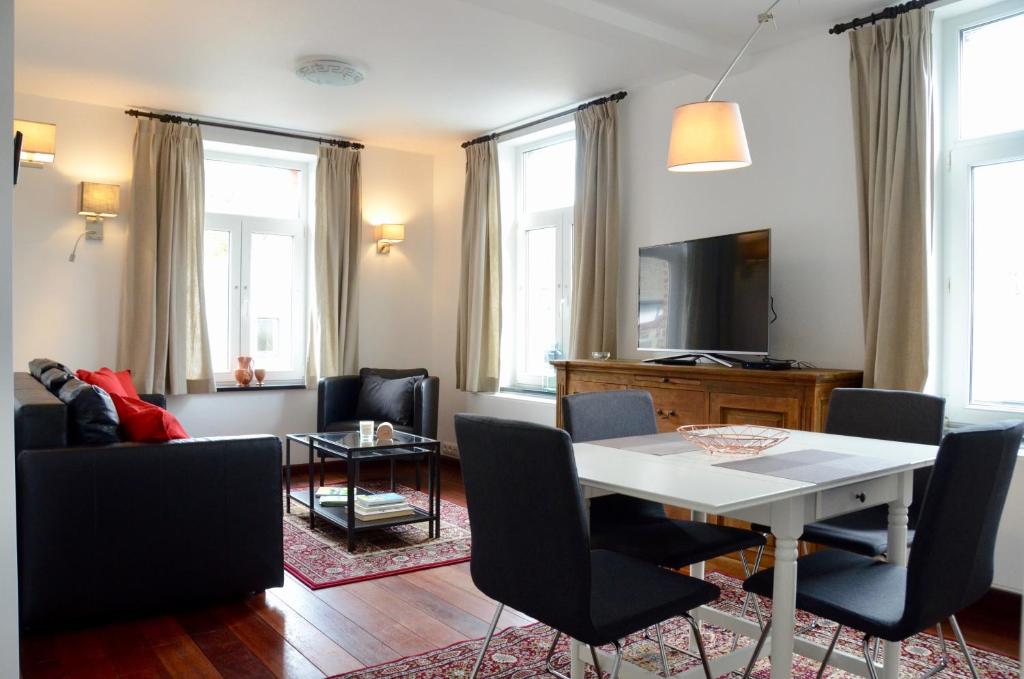 - un salon avec une table et des chaises blanches dans l'établissement Le Baron Apartments, à Stavelot