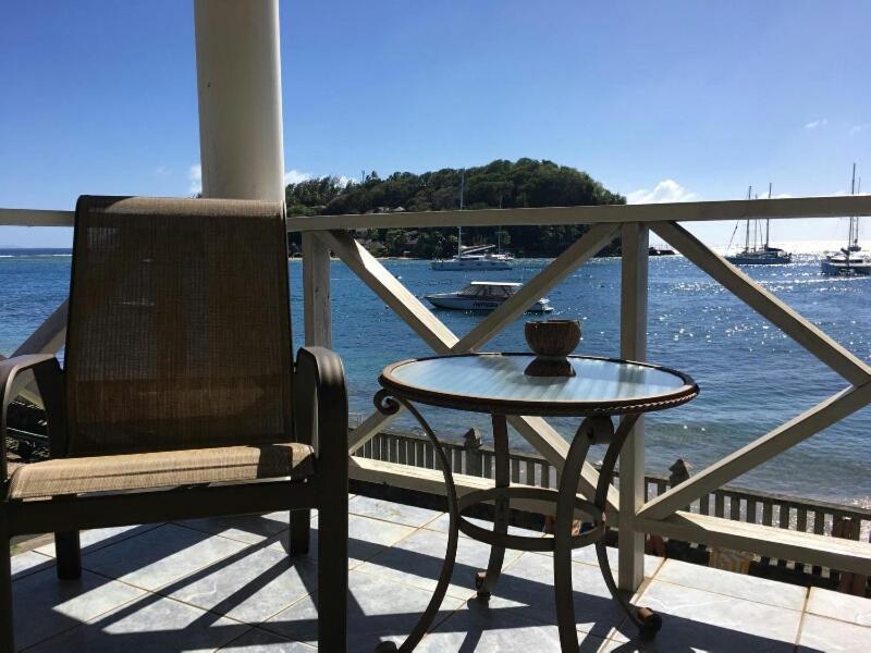 a table and a chair on a porch next to the water at Paradise Beach Hotel in Kingstown