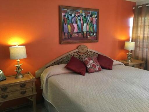 a bedroom with a bed with orange walls and two lamps at Paradise Beach Hotel in Kingstown
