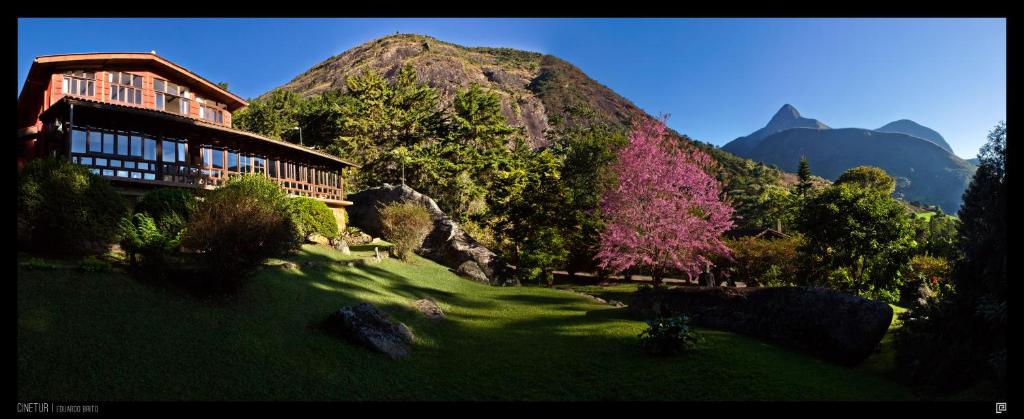 a building on a grass field with a mountain at Pousada Paraíso Açú in Itaipava