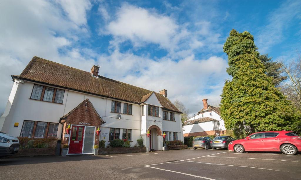 a white building with cars parked in a parking lot at Red Mullions Guest House in Oxford