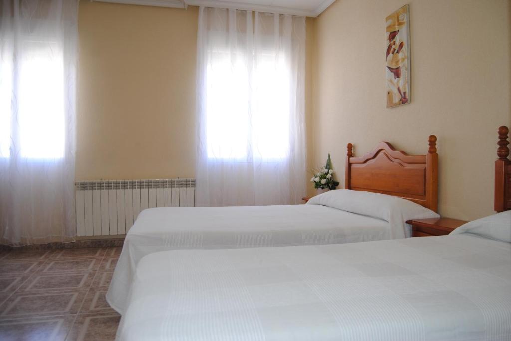 1 dormitorio con 2 camas y una ventana con cortinas en Hostal Ávila en Ocaña
