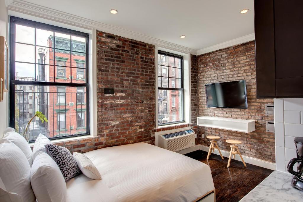a bedroom with a brick wall and a bed and windows at East Village Hotel in New York