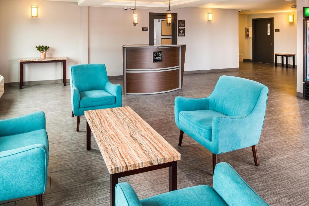 a waiting room with blue chairs and a table at Red Lion Inn and Suites Everett in Everett