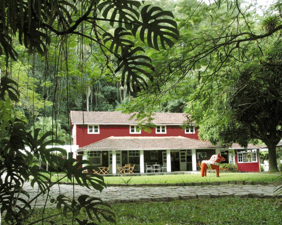 una casa roja con una persona parada frente a ella en Pequena Suécia, en Penedo