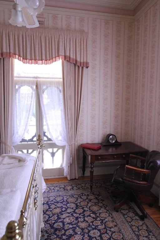 a bedroom with a bed and a desk and a window at Palm House in Maldon