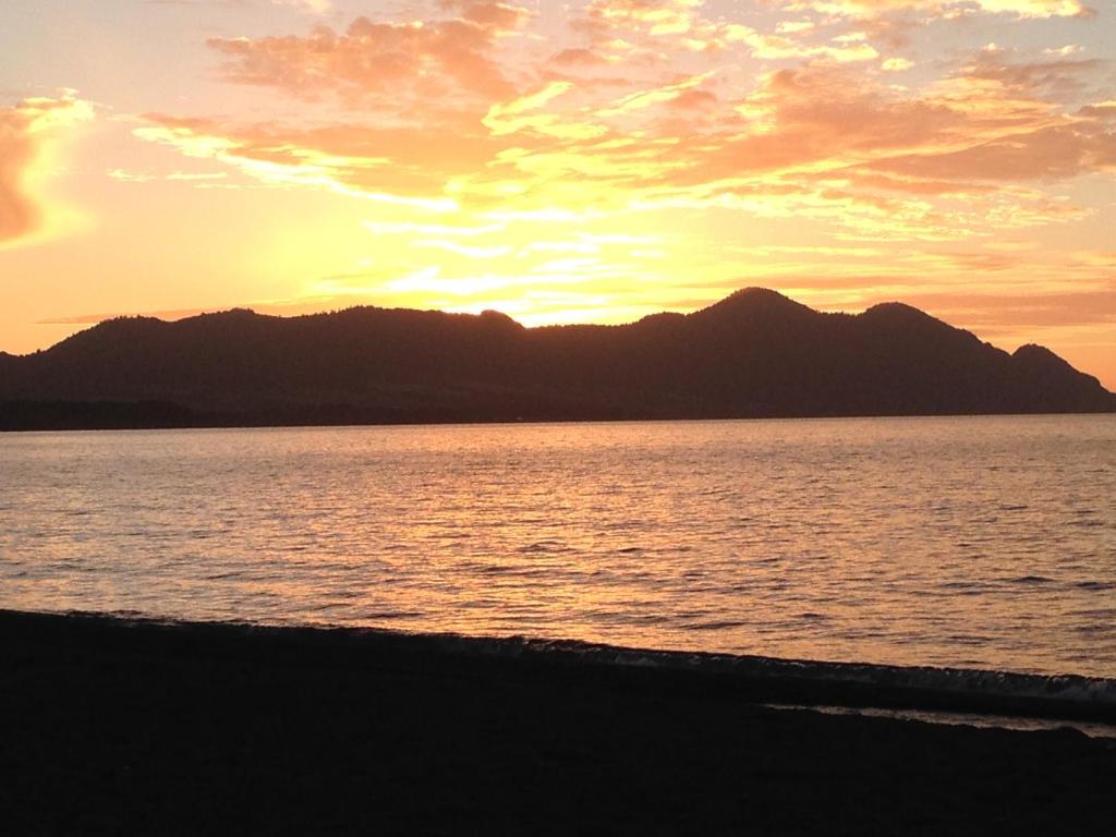 einen Sonnenuntergang über einem Wasserkörper mit Bergen im Hintergrund in der Unterkunft Turismo Montaña II in La Ensenada