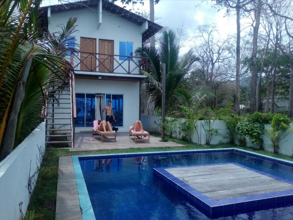 a villa with a swimming pool in front of a house at Hostal Hilltop Capurgana in Capurganá