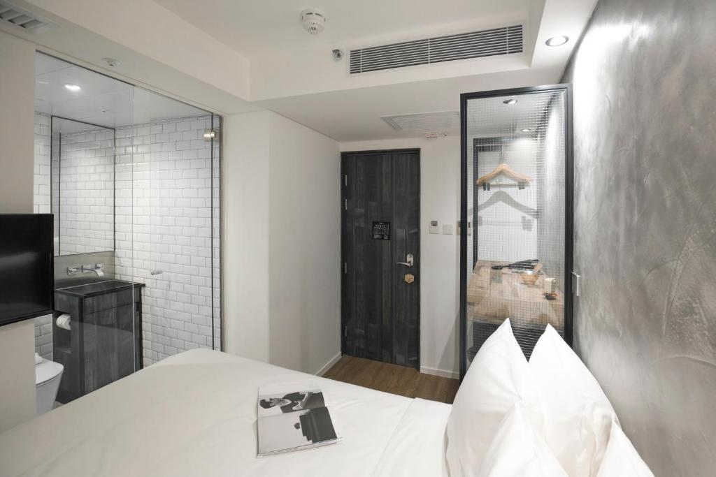 una camera con letto bianco e bagno di Hotel Hart a Hong Kong