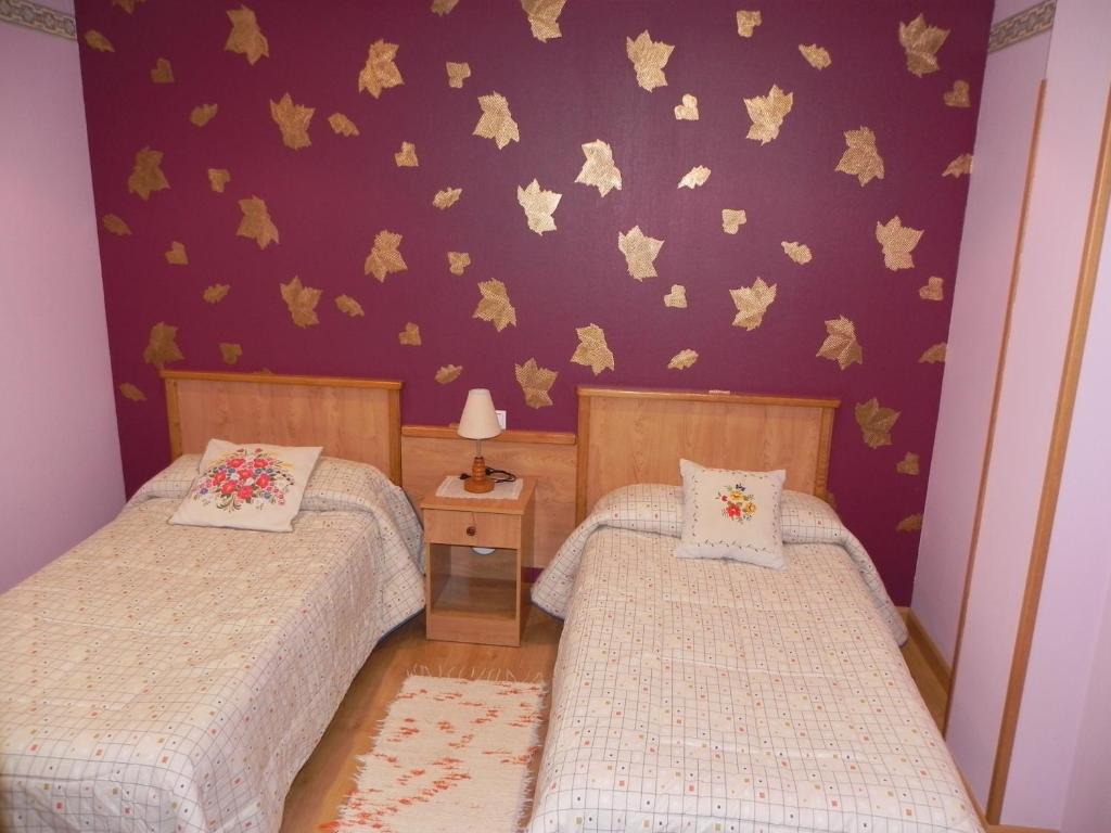 two twin beds in a bedroom with a purple wall at O Lar de Carmiña in Devesa