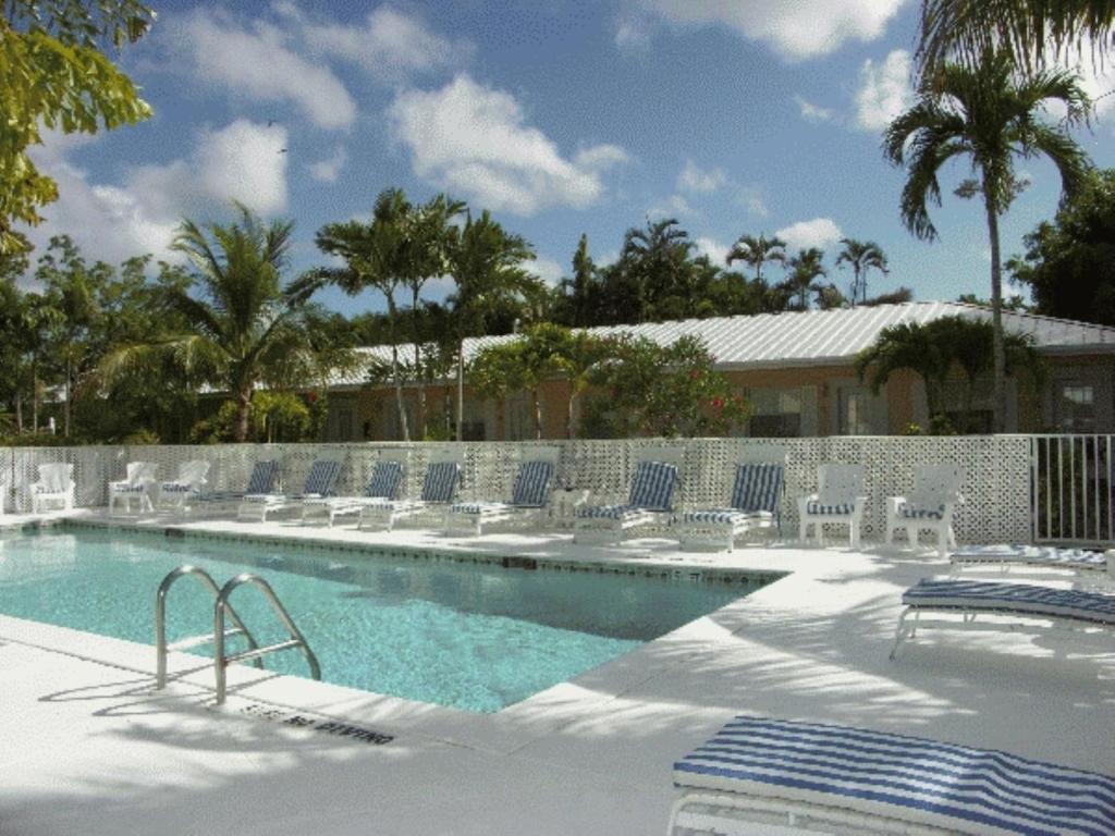 a swimming pool with blue chairs and a fence at Marco Island Lakeside Inn in Marco Island